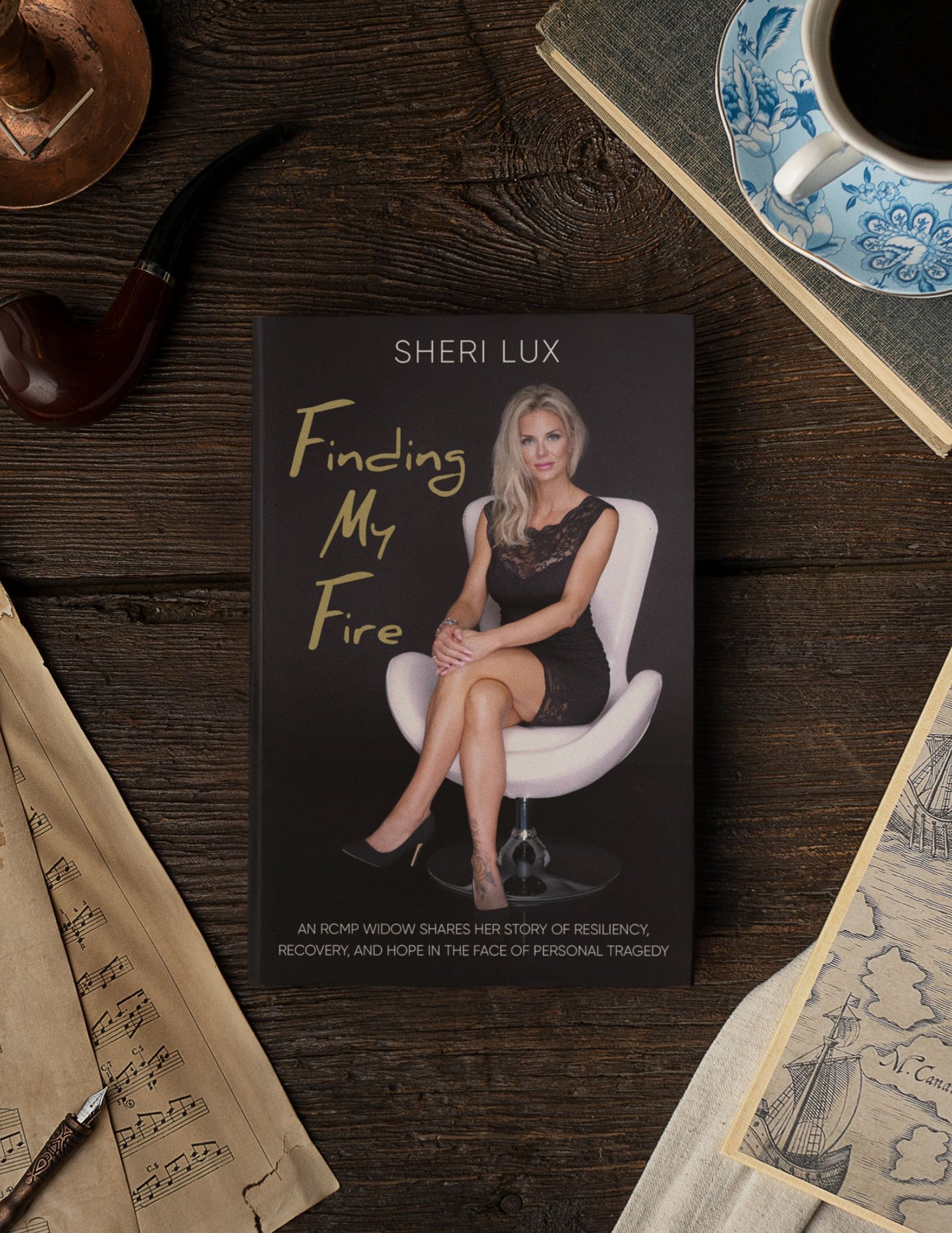 Book titled 'Finding My Fire' by Sheri Lux on a wooden surface with a cup and saucer.