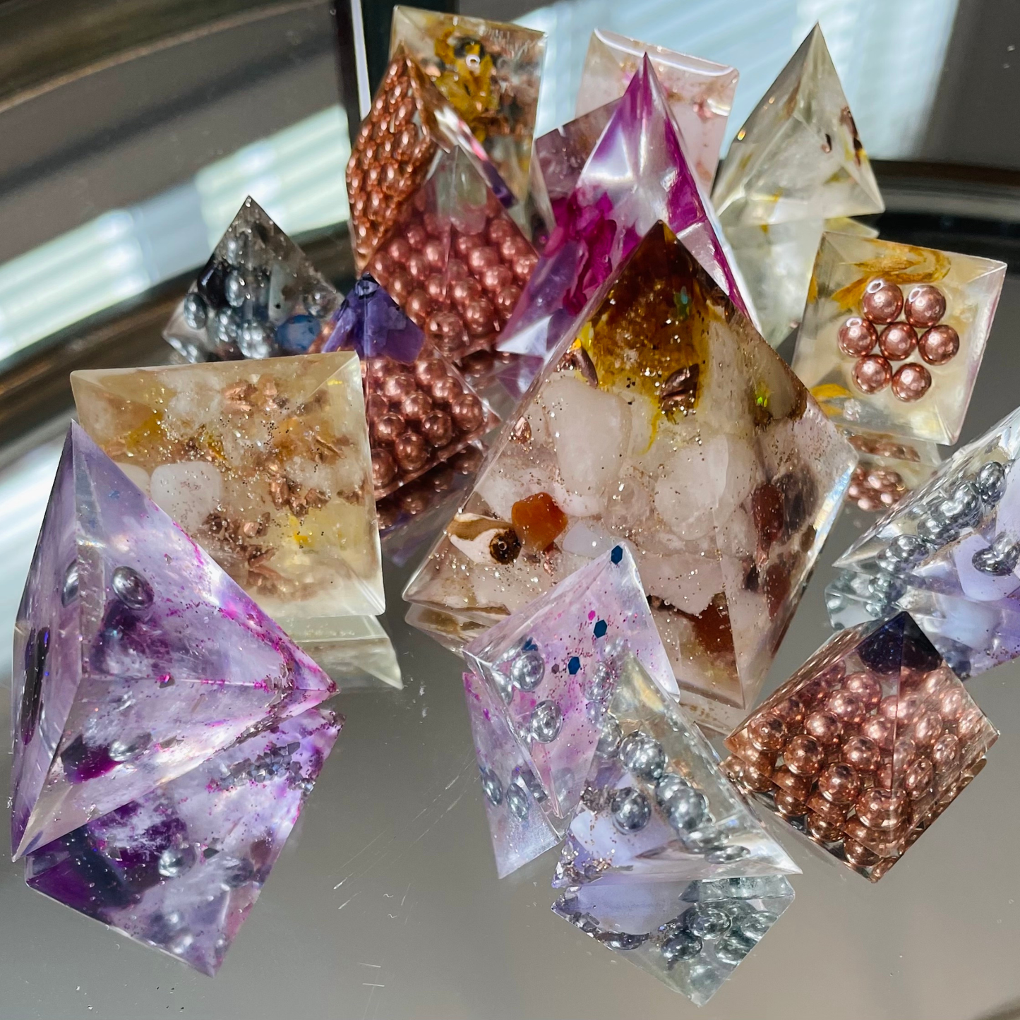A cluster of colorful and vibrant organite crystals on a mirrored table. 