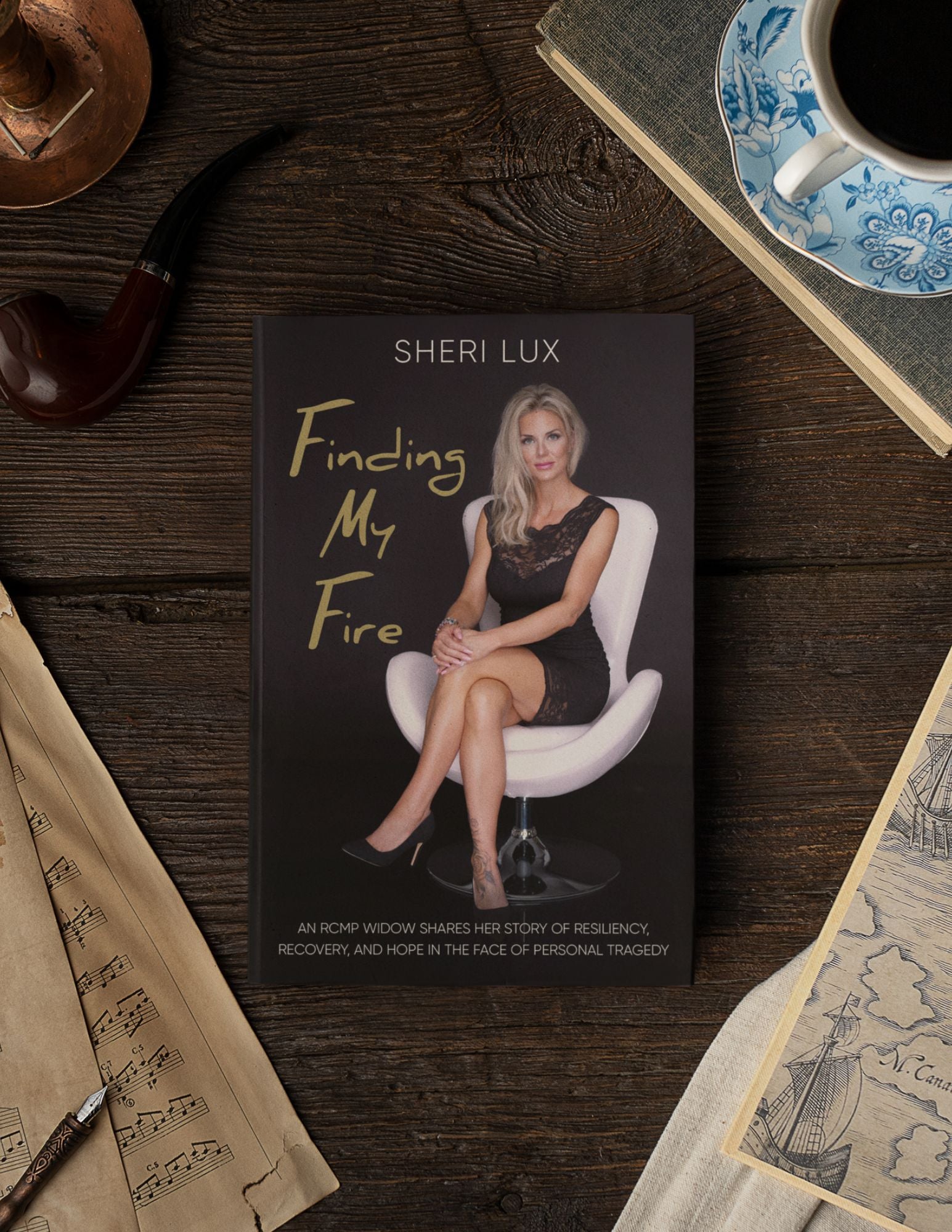 Book titled 'Finding My Fire' by Sheri Lux on a wooden surface with a cup and saucer.