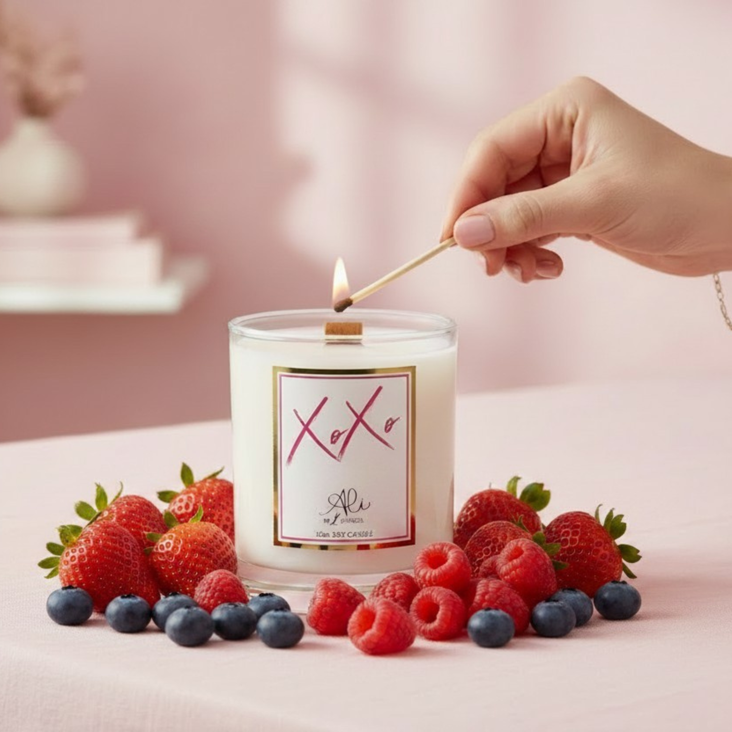 Candle being lit with a match, surrounded by strawberries and raspberries on a pink background