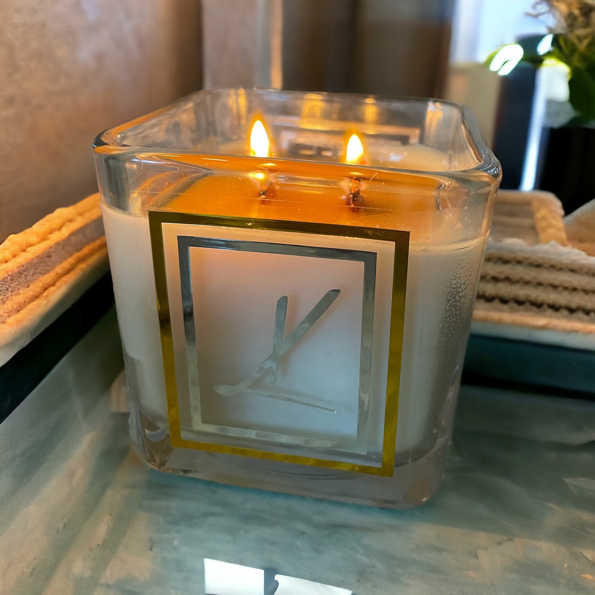 Candle in a glass container with a decorative label on a marble surface
