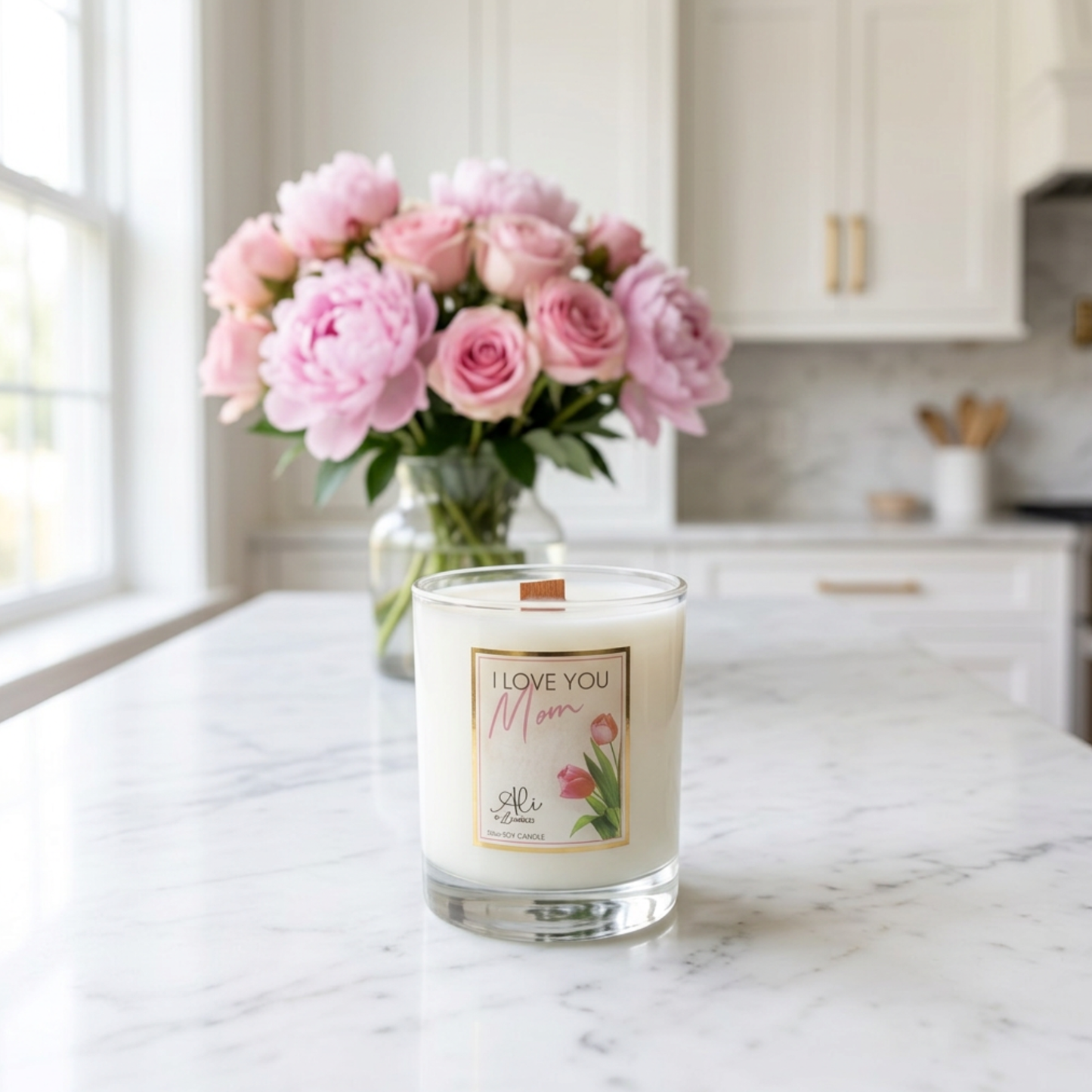 Candle with 'I Love You Mom' label and pink flowers on a kitchen counter